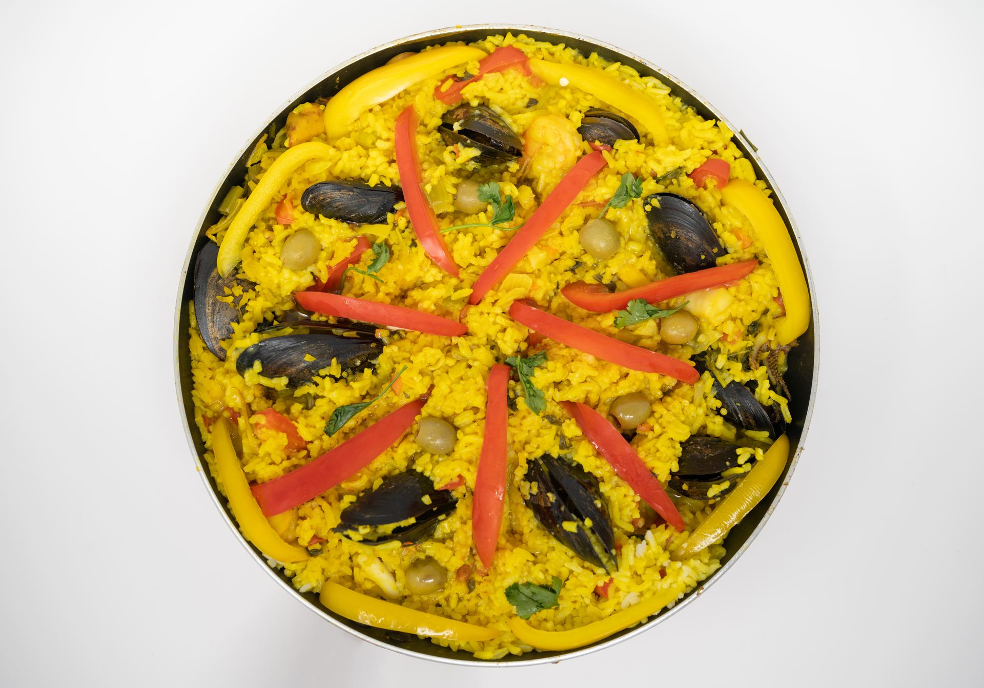 A large pan of seafood paella with mussels and red pepper strips