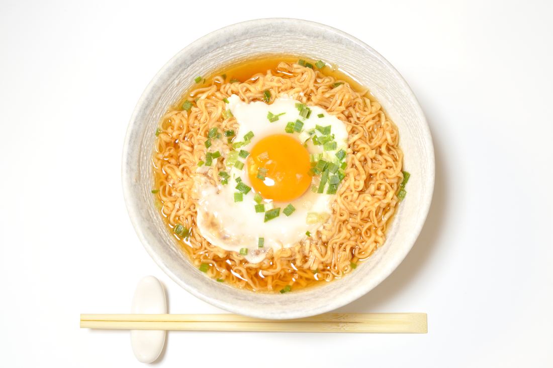 A bowl of instant chicken ramen topped with a fried egg and green onion