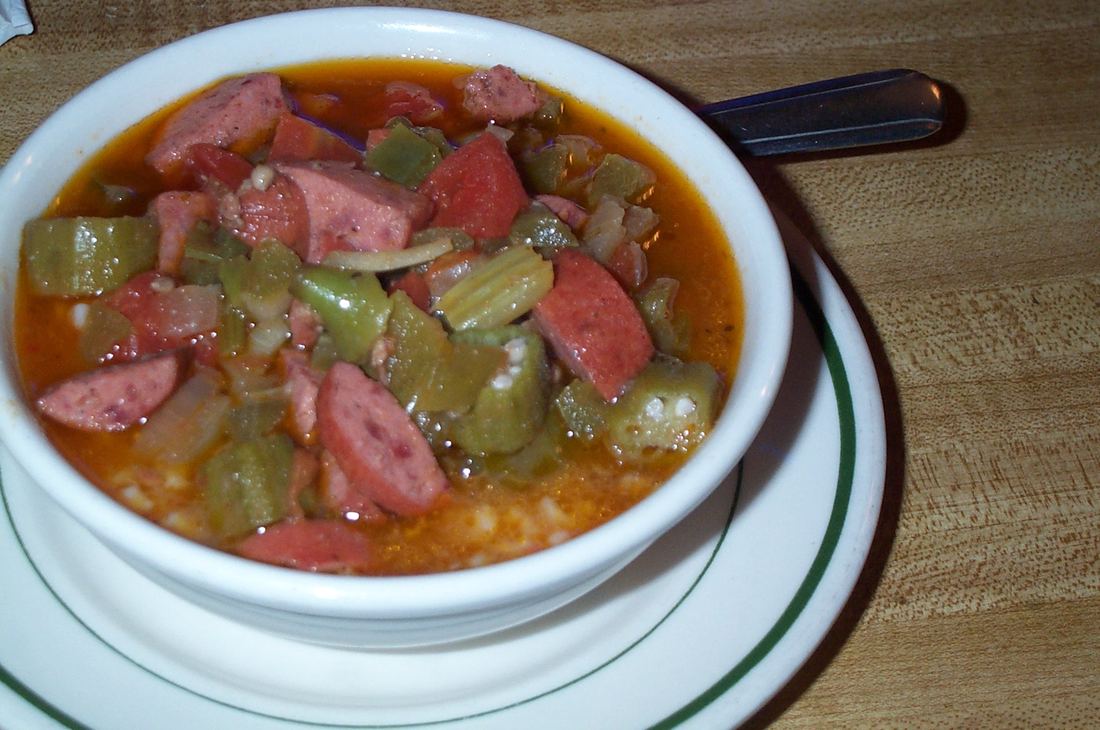 A bowl of gumbo with sliced sausage and okra